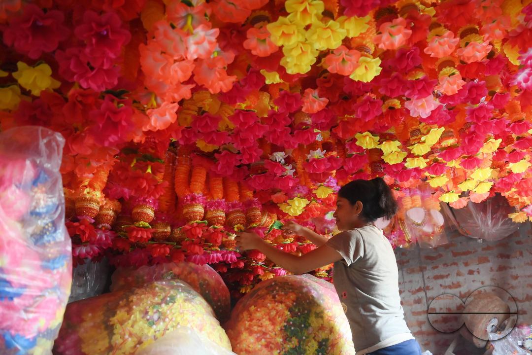 A worker arranging plastic garlands for sale at a stall ahead of the festive