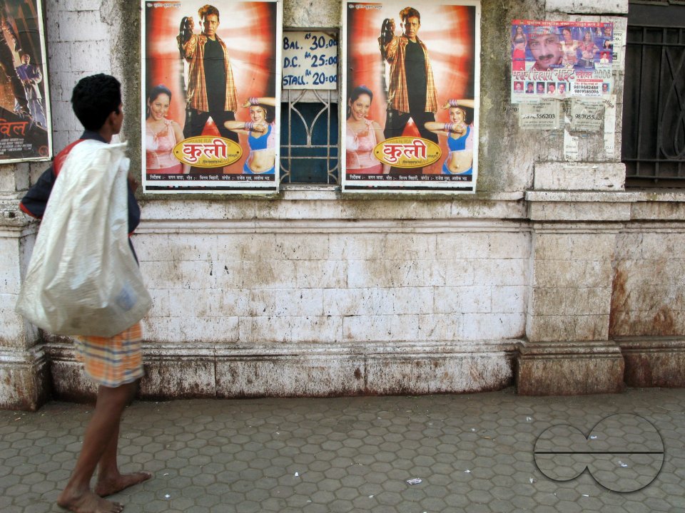 INDIA.People walking past an old picture house in Mumbai.