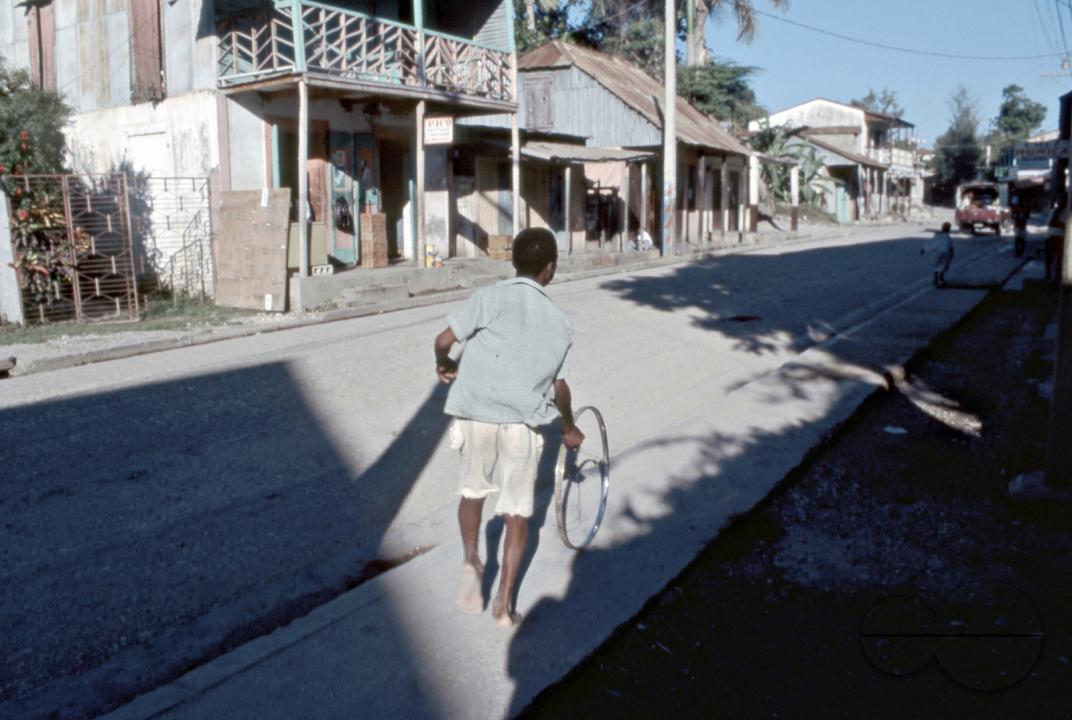 HAITI YOUTH PLAYING WITH A WHEEL IN THE STREETS OF JACMEL. Photo  Julio Etchart