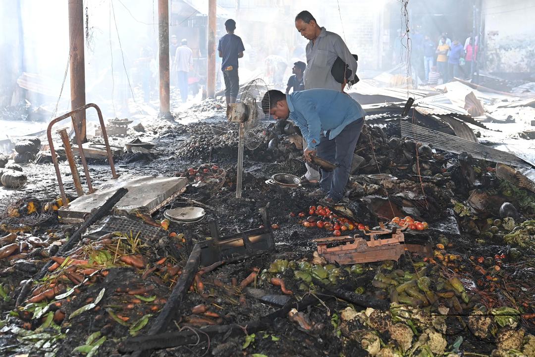 Shop owners and vendors are seen in front of their burnt shops and vegetables stalls in Battala market, the second biggest market in Tripura
