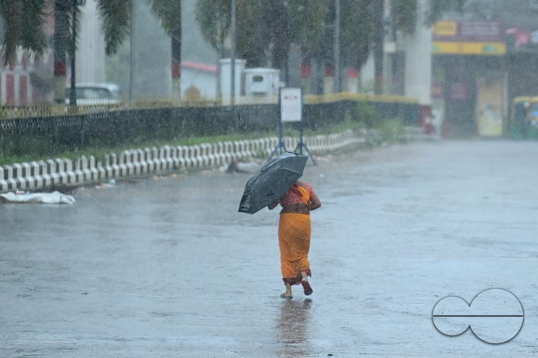 A woman crossing a deserted road in heavy rain during Cyclone Remal in Agartala