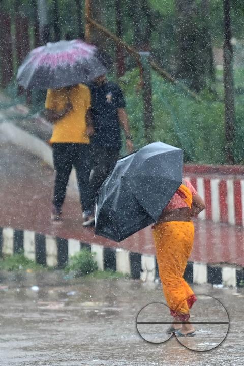 People crossing a deserted road in heavy rain during Cyclone Remal in Agartala