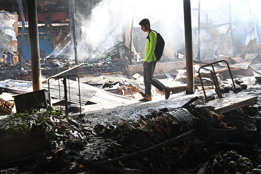 Shop owners and vendors are seen in front of their burnt shops and vegetables stalls in Battala market, the second biggest market in Tripura