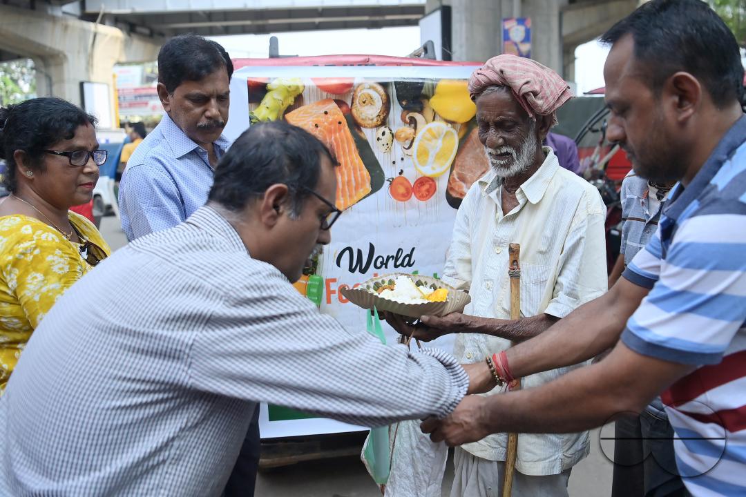 People get food from a social worker on World Food Safety Day, organised by "Roti Bank Foundation", in Agartala