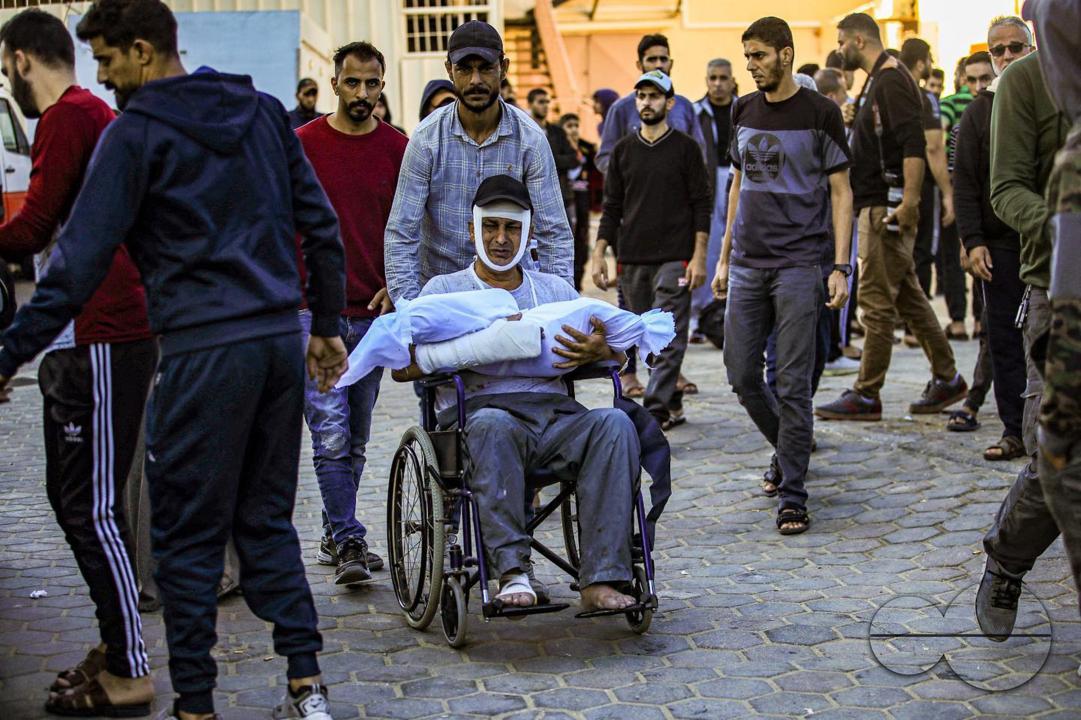 A Palestinian father carries his child who was killed during an Israeli air strike on his home in the Nuseirat camp in central Gaza City