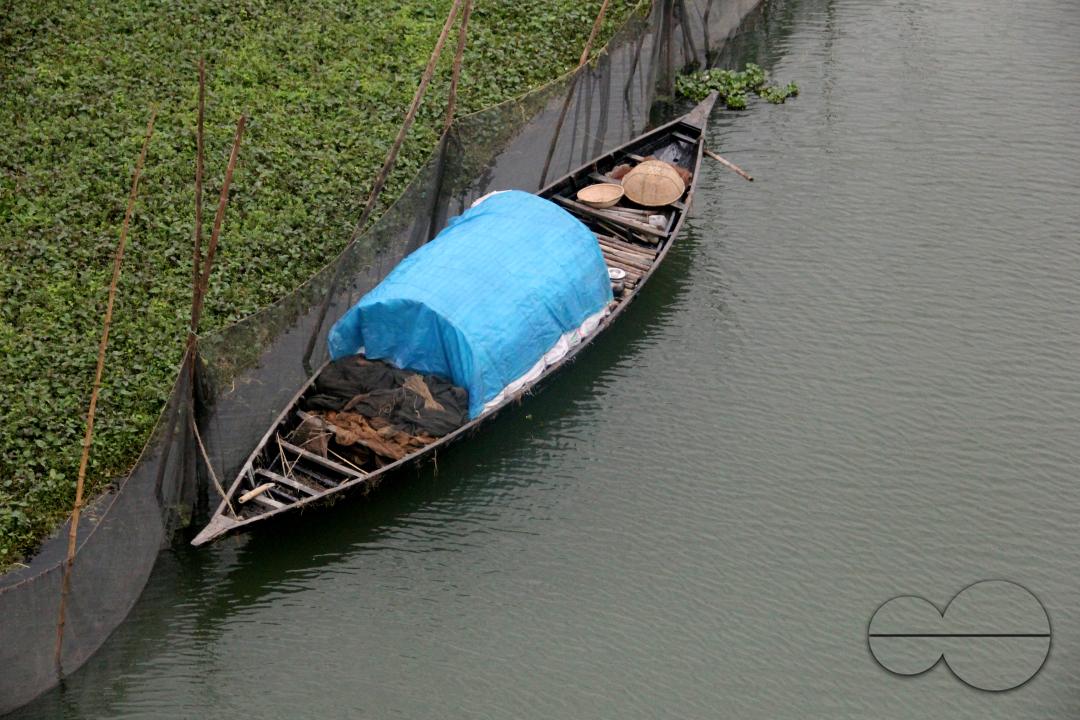 A paddle boat tied near a river in rural Bangladesh