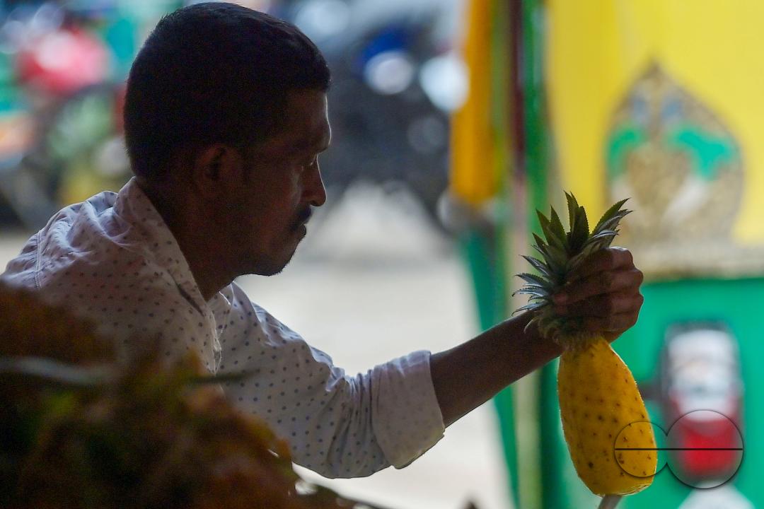 A vendor in Agartala sells fresh pineapples, a renowned summer fruit from Tripura, at a bustling roadside fruit market