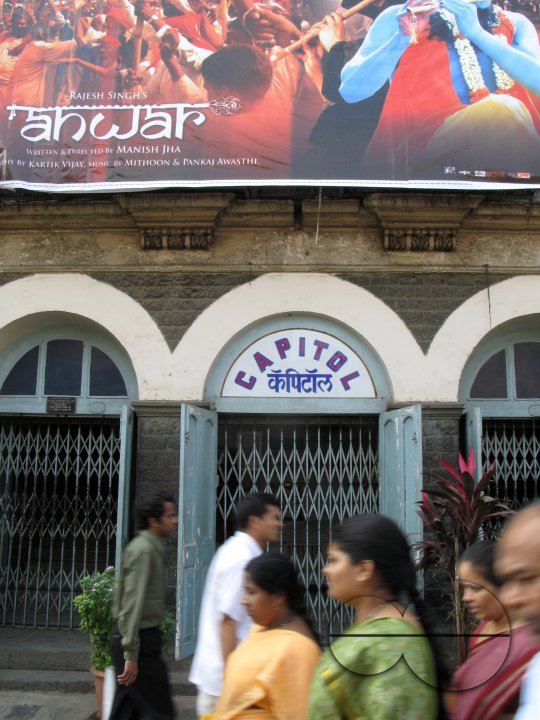 INDIA.People walking past an old picture house in Mumbai.