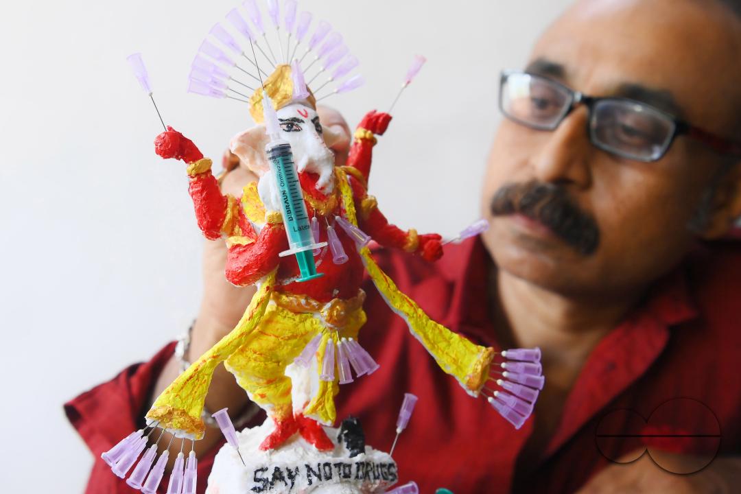 Samiran De, an artist works on an idol of Lord Ganesha made with soup and syringe needles to alert people against drugs, ahead of Ganesh Chaturthi festival, in Agartala
