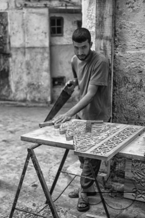 An artisan carpenter making fretwork panels on a medina street in Fez
