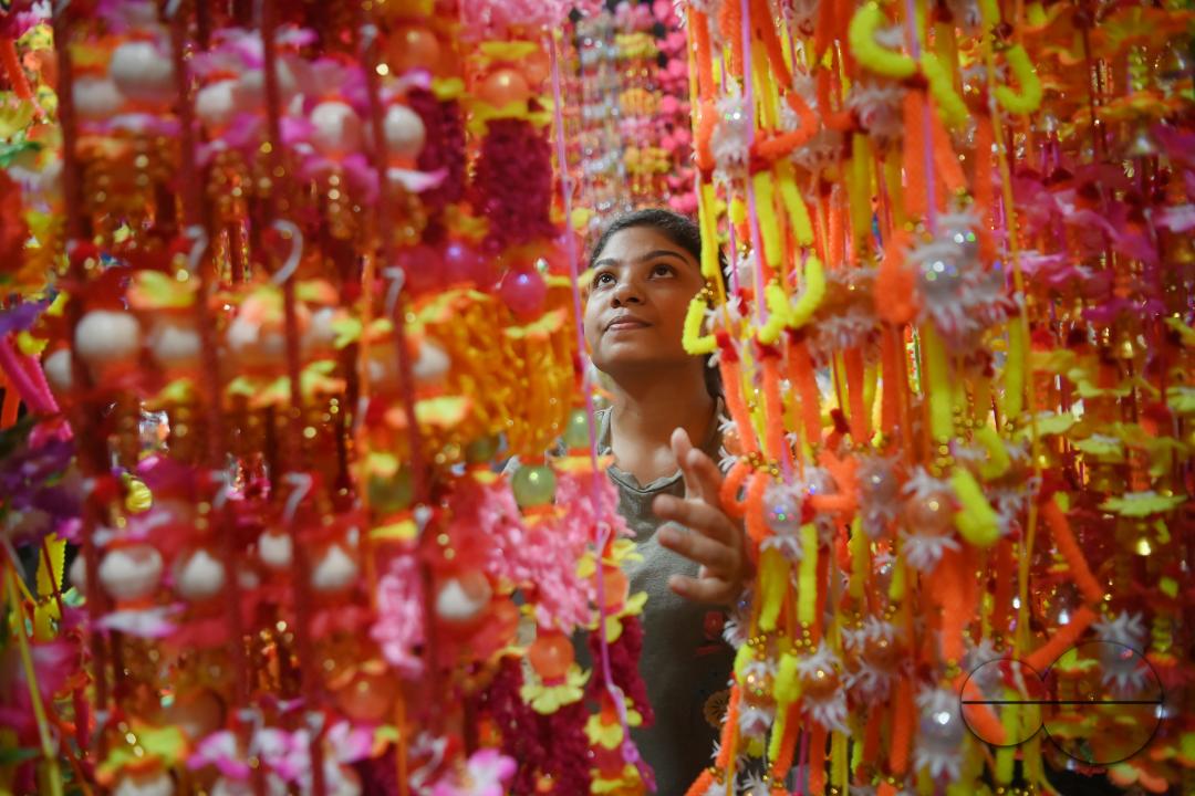 A worker arranging plastic garlands for sale at a stall ahead of the festive