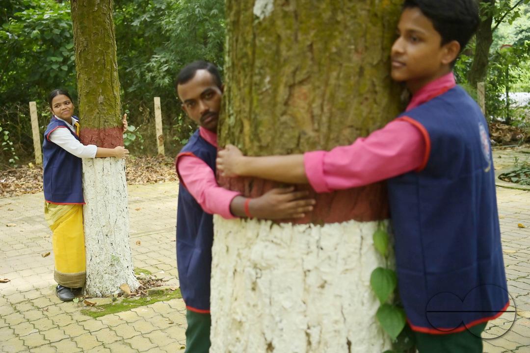 NSS (National Service Scheme) volunteers and school students of Netaji Subhas Vidyaniketan hug trees on the eve of World Nature Conservation Day