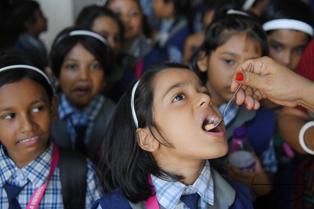 A schoolteacher is giving deworming tablets to the students in a school during the special program of Mukhyamantri Sustho Shoishob, Sustho Kaishore Abhiyan (MSSSKA 5'0) for National Deworming Day