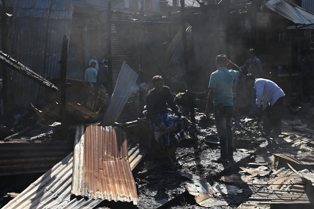 Shop owners and vendors are seen in front of their burnt shops and vegetables stalls in Battala market, the second biggest market in Tripura