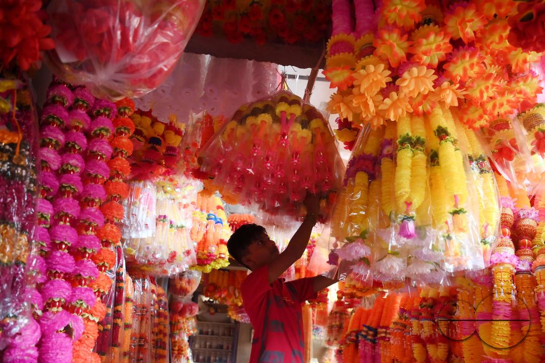 A worker arranging plastic garlands for sale at a stall ahead of the festive