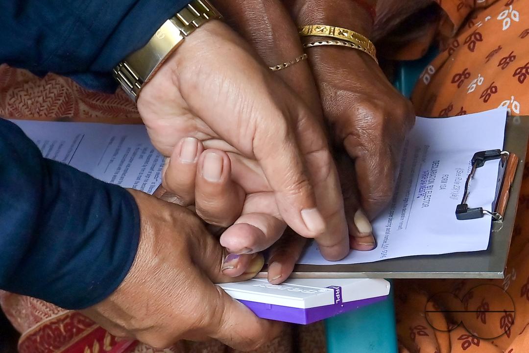 An old lady aged 104, going through the pre vote procedures before casting her postal ballot vote with the assistance of her family members at her house in front of the team of election officials and security personnel in Agartala