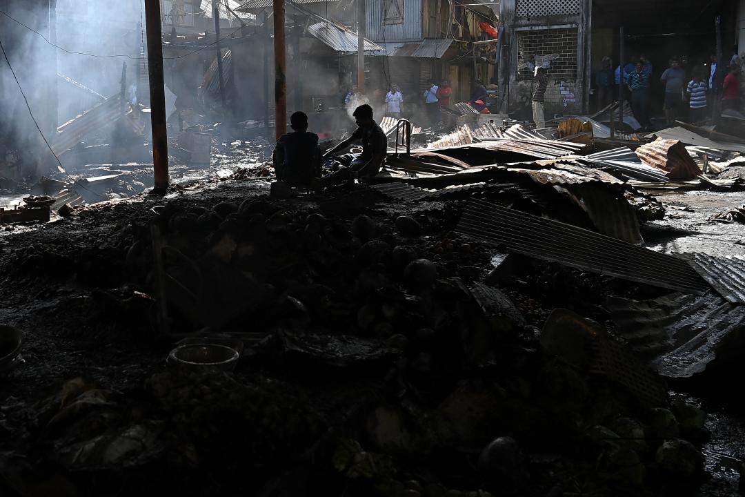 Shop owners and vendors are seen in front of their burnt shops and vegetables stalls in Battala market, the second biggest market in Tripura