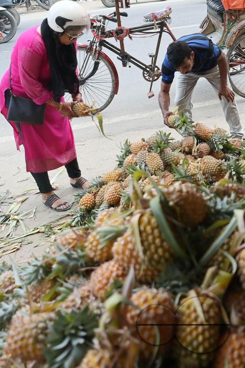 People purchase pineapples, a renowned summer fruit of Tripura, from a vendor's stall at a bustling roadside fruit market in Agartala