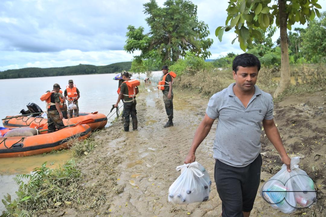 Assam Rifles personnel going to a relief camp through flooded water to distribute food items to flood victims at relief camps of Amarpur city, 82km away from Agartala