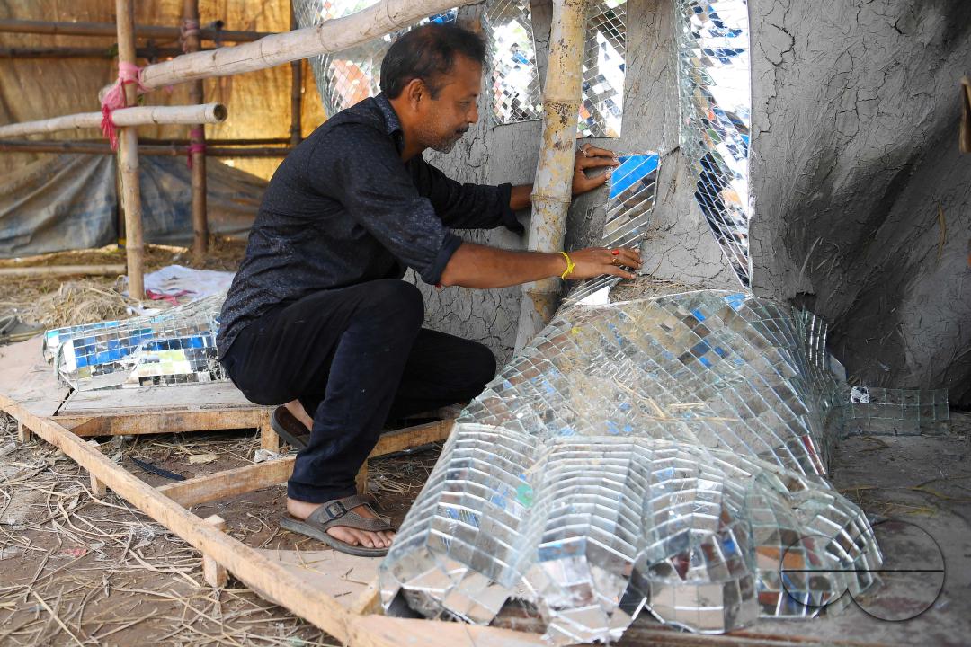 An artist is pasting glass pieces to make a 41 feet tall Ganesh idol, fully covered by glass, ahead of Ganesh Chaturthi festival in a pandal in Ranir bazar