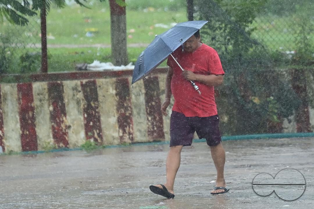 People crossing a deserted road in heavy rain during Cyclone Remal in Agartala
