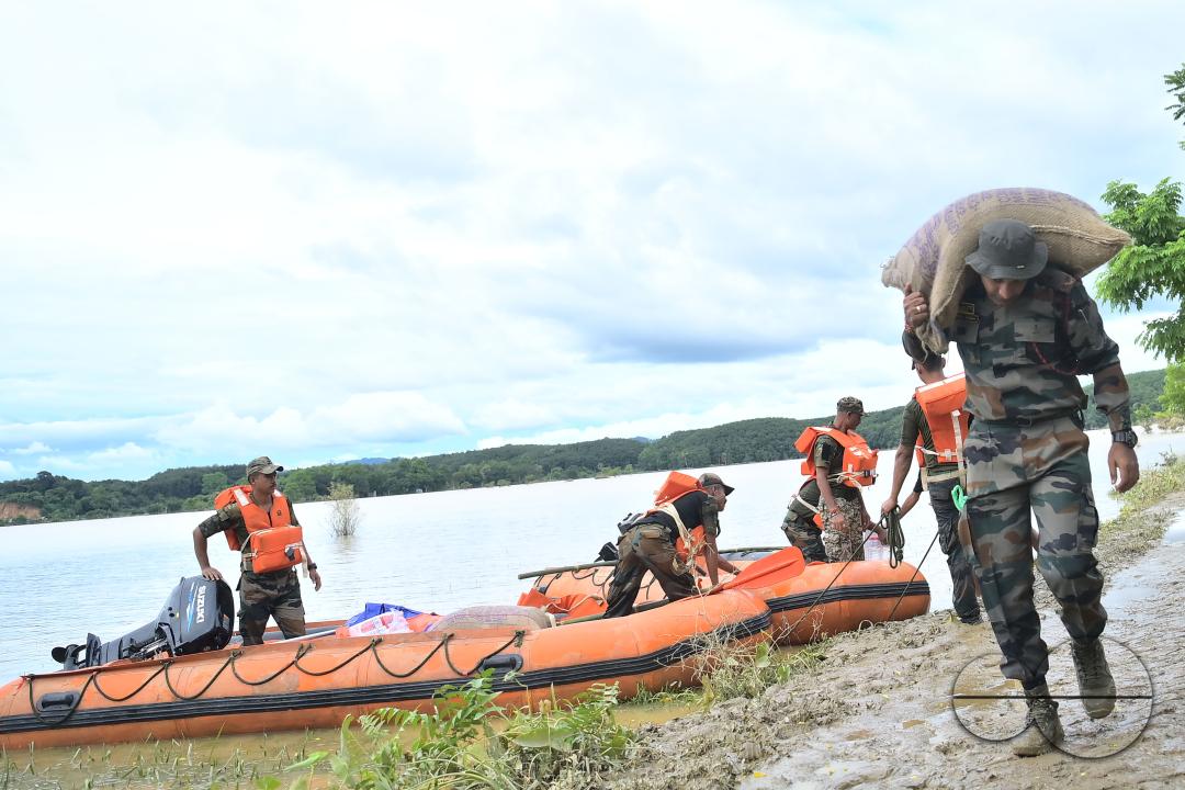 Assam Rifles personnel going to a relief camp through flooded water to distribute food items to flood victims at relief camps of Amarpur city, 82km away from Agartala