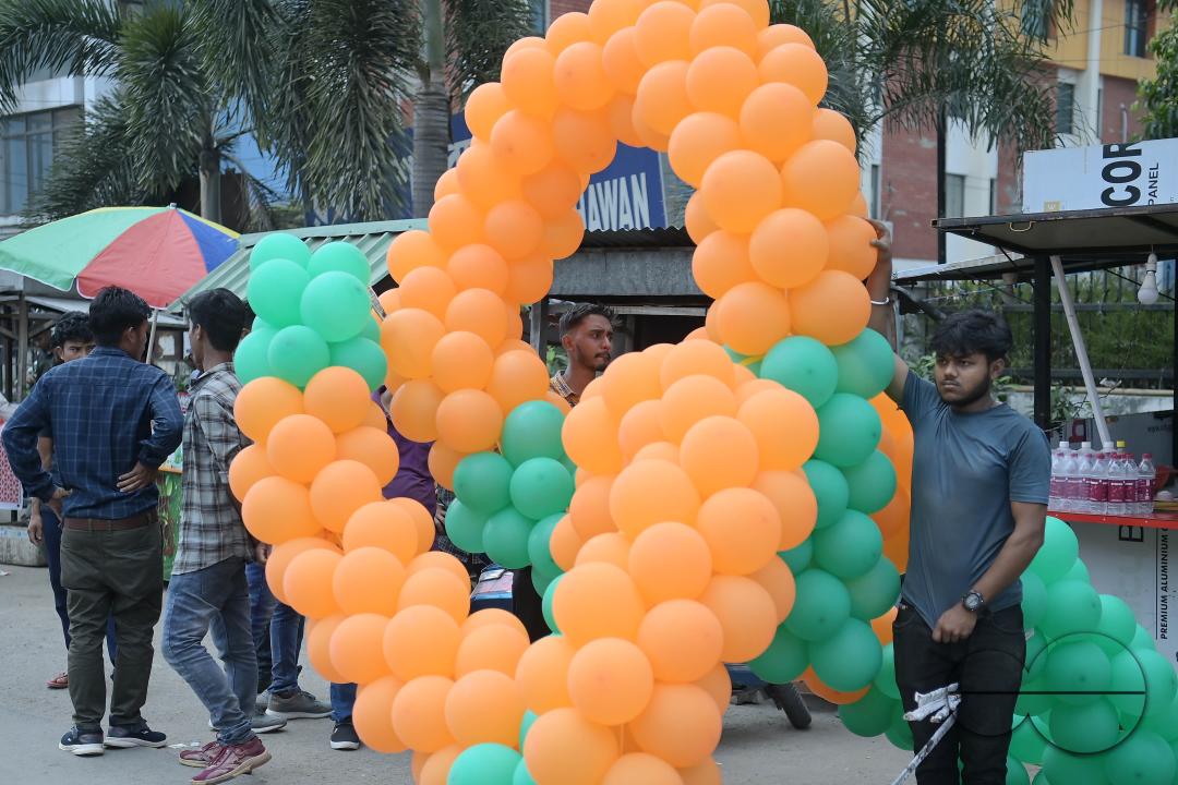 Supporters of the BJP are seen decorating balloons in the party's colours at a rally featuring Tripura Chief Minister Manik Saha, former CM and BJP candidate Biplab Kumar Deb, and Kriti Singh, alongside other leaders, during an election campaign rally in