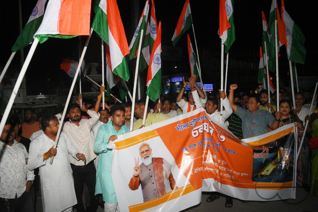 BJP party leaders, workers and the general public celebrate with the Indian flag in front of a LCD TV during the live stream of the successful lunar landing of the Chandrayaan-3 spacecraft on the south pole of the Moon, in Agartala