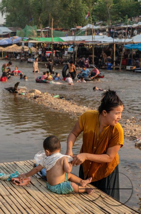 Thai and Burmese families swimming and playing in the Thailand - Myanmar Moei river border near Mae Sot, Thailand.