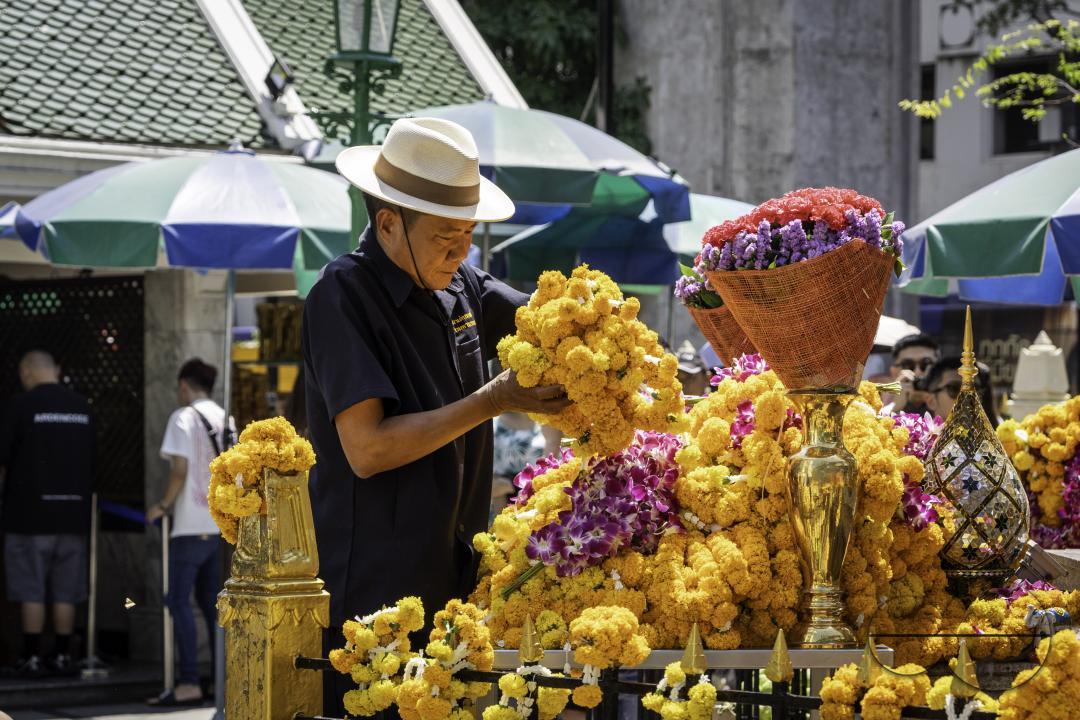 Staff from the shrine picking up flowers before putting them in the trash, at the Erawan Shrine, in downtown Bangkok