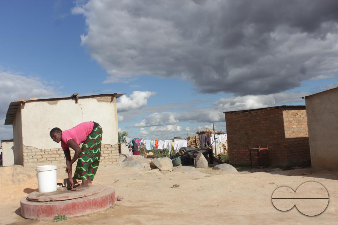 A woman drawing water from from a well at Hopeley Farm Settlement in Harare