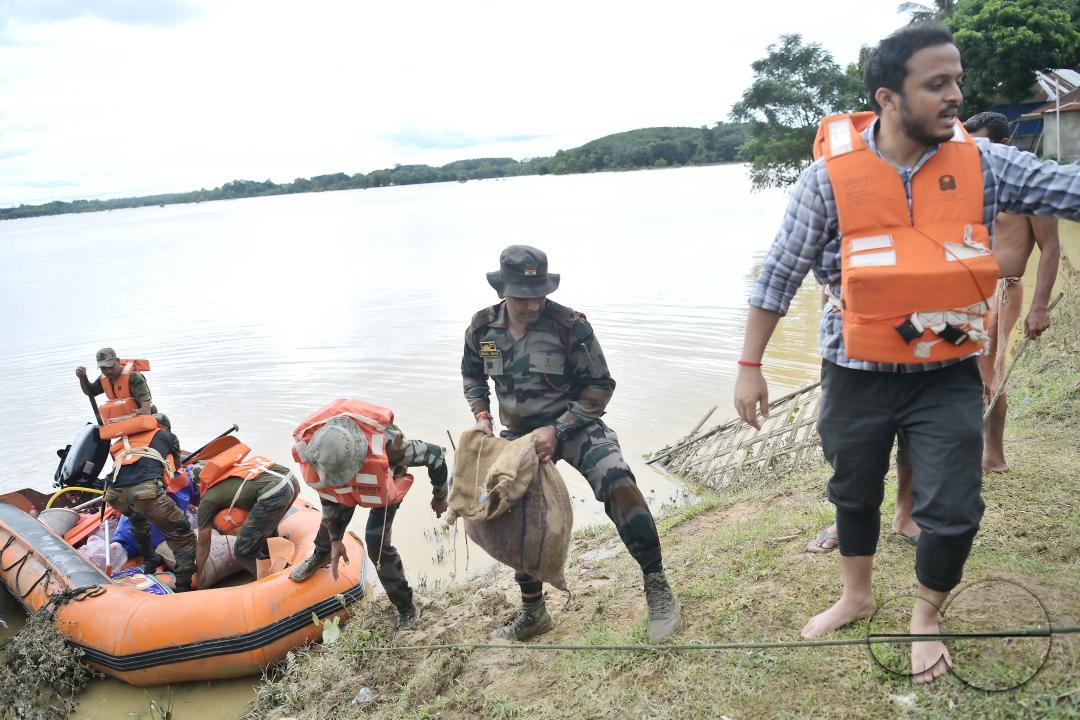 Assam Rifles personnel going to a relief camp through flooded water to distribute food items to flood victims at relief camps of Amarpur city, 82km away from Agartala