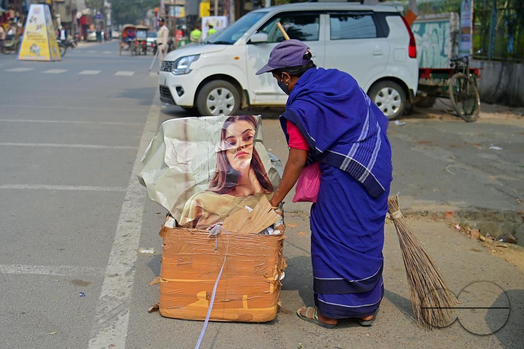 An employee of the municipality sweeps and collects garbage into a collection box in Agartala