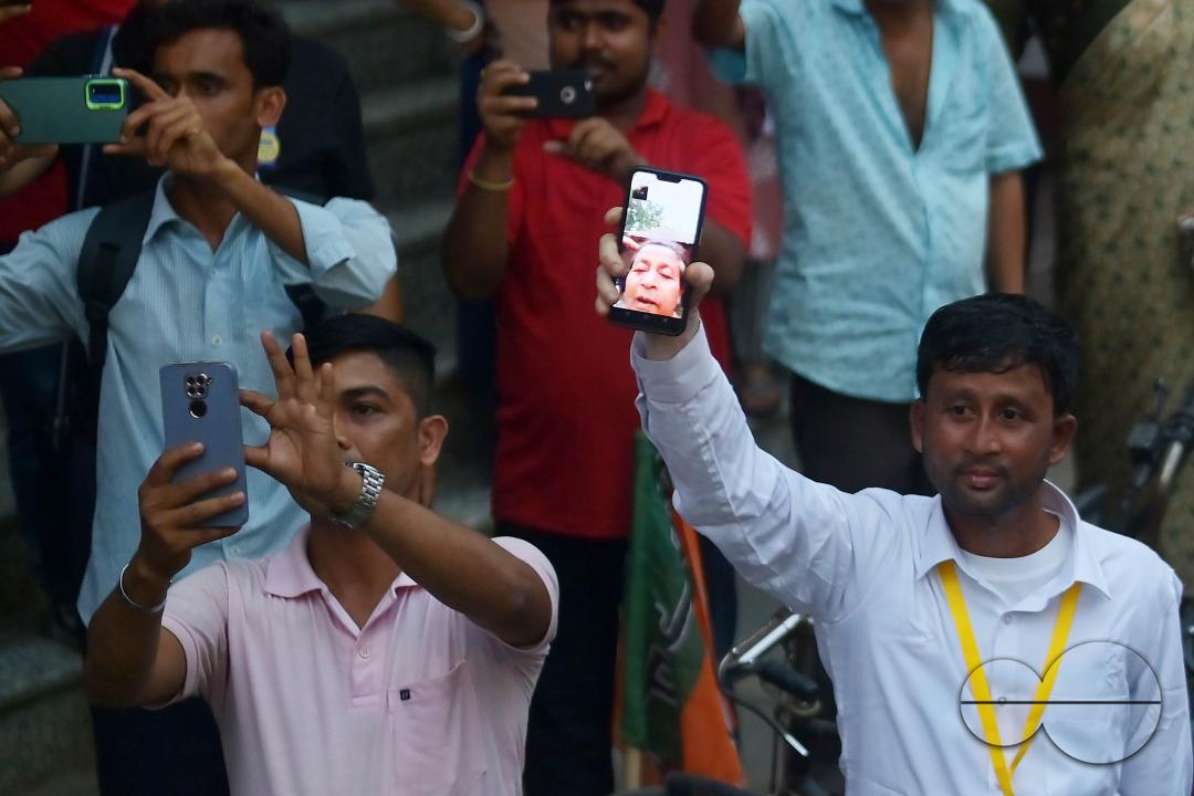 An endearing sight unfolds in Agartala as a supporter shares the live moment of Congress leaders Priyanka Gandhi Vadra, Sudip Roy Barman, and Ashish Sahain through his phone camera with his mother during a lively roadshow preceding the Lok Sabha election
