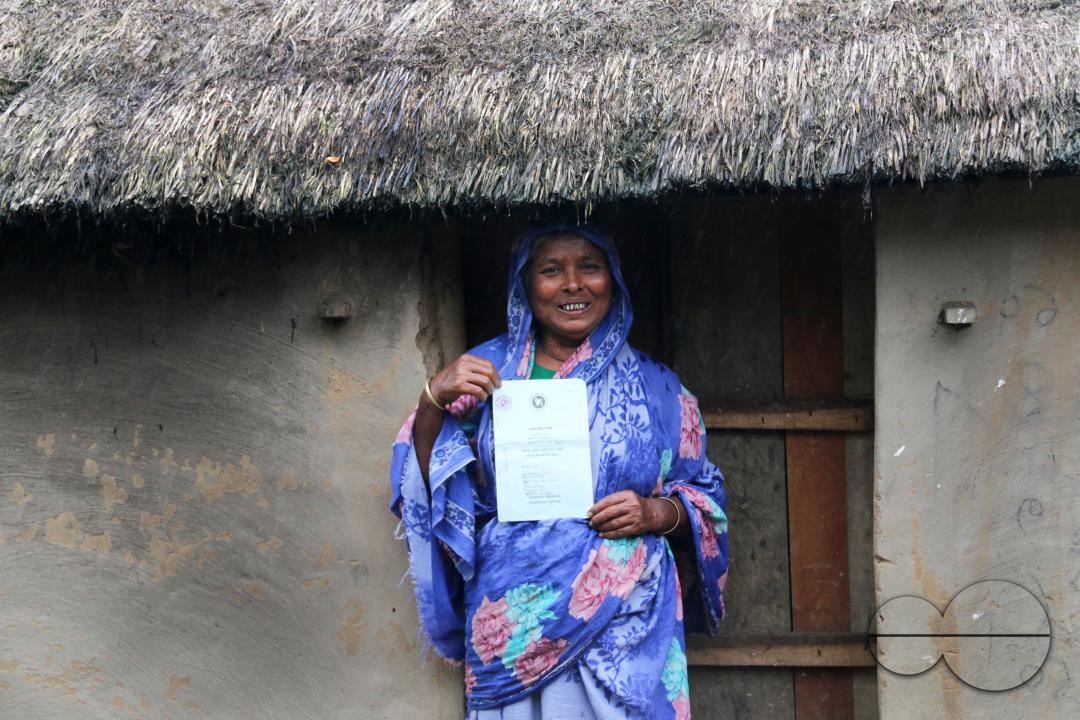 Portrait of a rural Bangladeshi woman showing her accommodation and old age allowances which are donated by the government