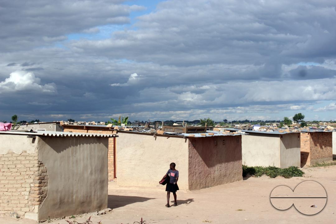 A young girl walking past a row of houses at Hopeley Farm Settlement
