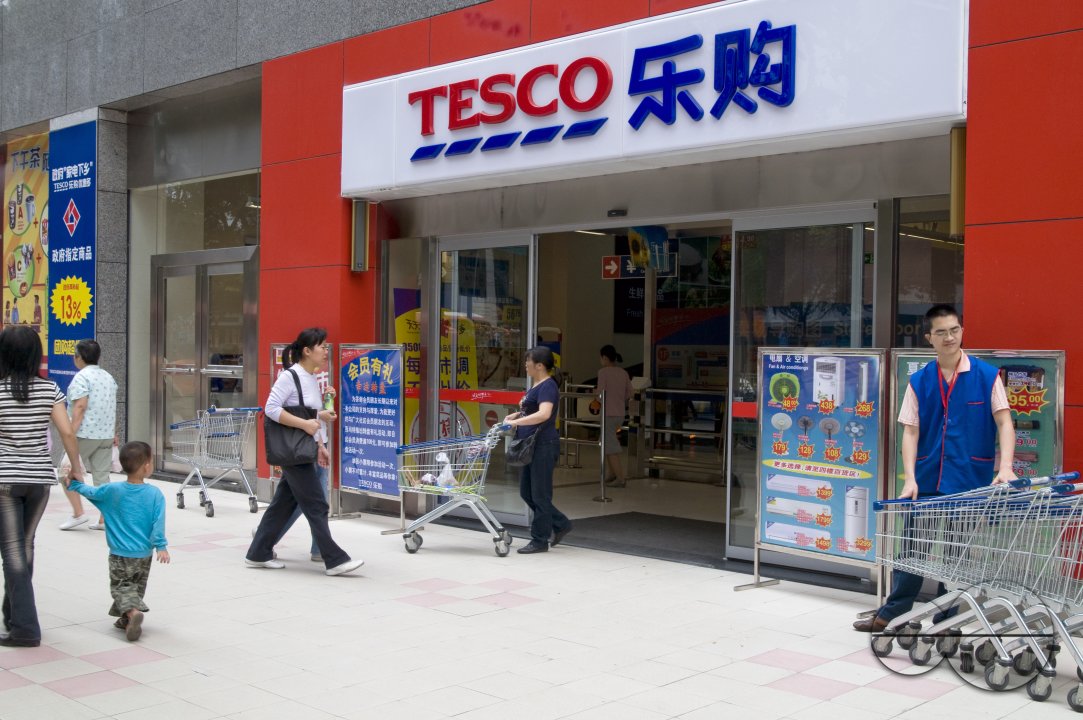 CHINA Shoppers walking past a Tesco store in Guangzhou, Guangdong province.
