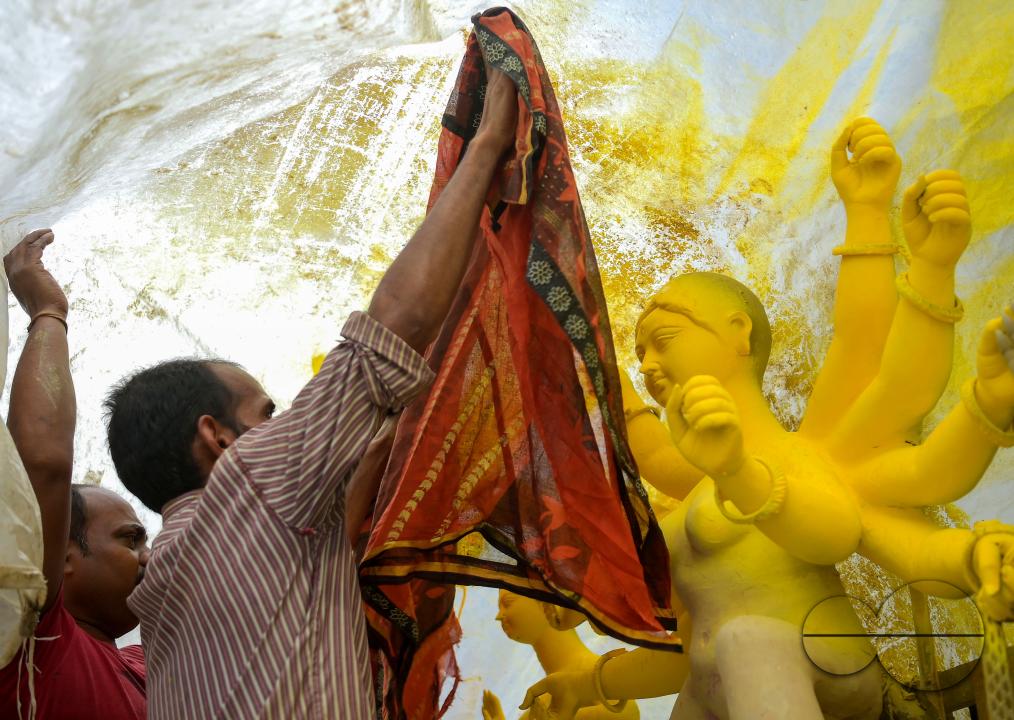 Idol makers are covering an idol of the Mother Goddess Durga during a rainstorm in a studio, ahead of the Durga Puja festival in Agartala, Tripura, India.