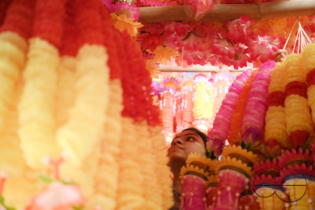 A worker arranging plastic garlands for sale at a stall ahead of the festive