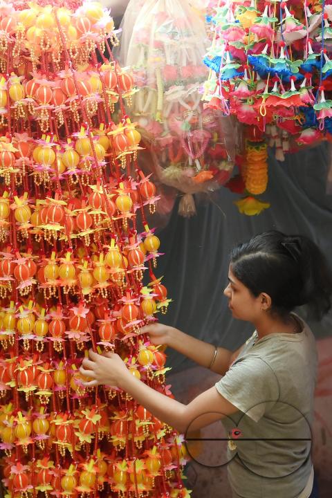 A worker arranging plastic garlands for sale at a stall ahead of the festive