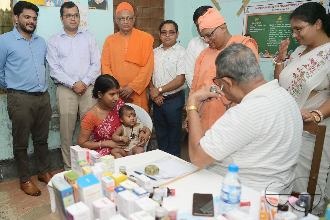 A doctor examining a boy during a visit by Swami Shubhakarananda (Maharaj) - Secretary of Ramakrishna Mission, along with Mayor Deepak Majumdar, the District Magistrate, and other officials inspect a health camp for flood victims at a temporary relief ca