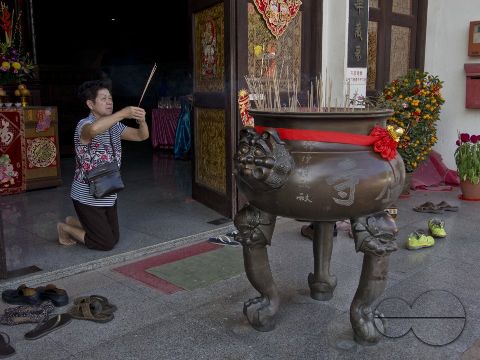 Elderly woman paying respect at a temple on the eve of Chinese New Year in Singapore