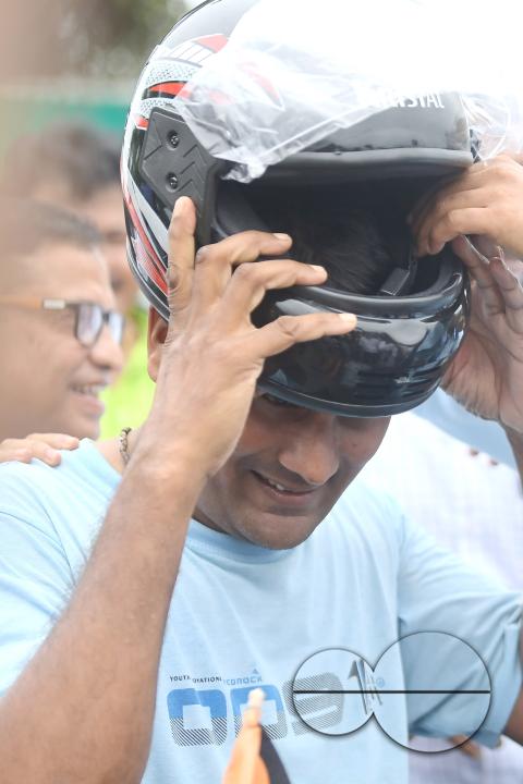 A traffic official puts a helmet on a motorist during a helmet distribution program and a road safety awareness campaign organised by the Tripura Transport Department at Agartala
