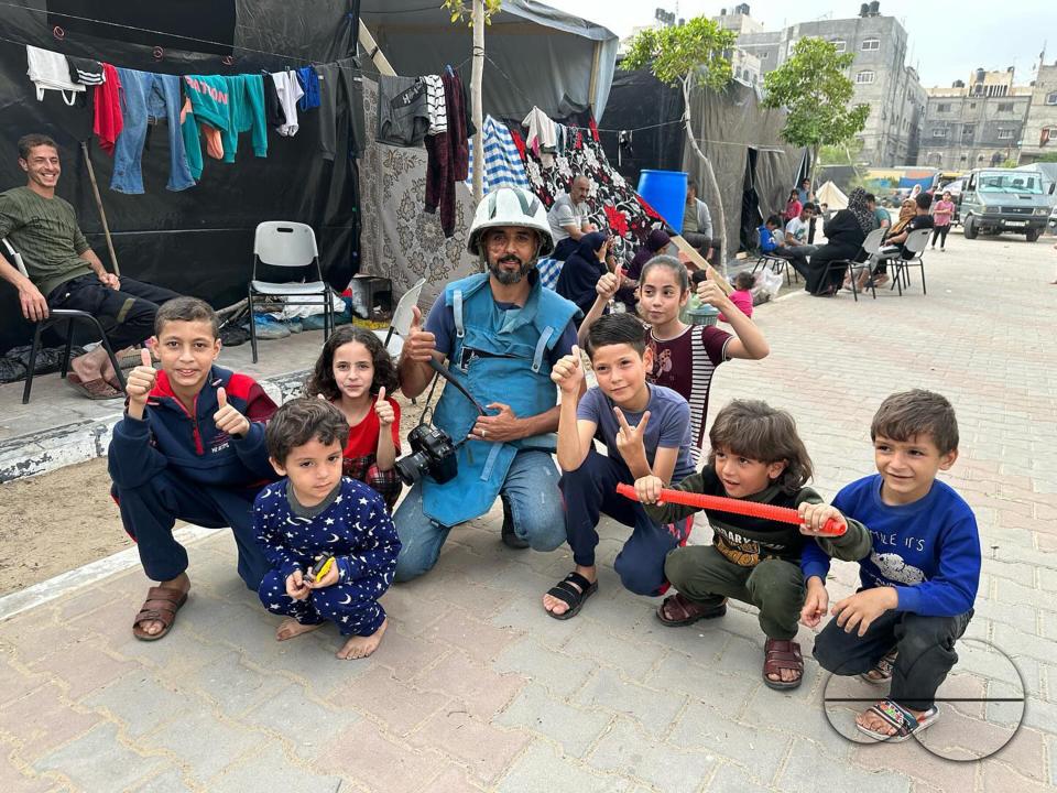 Majority World photographer Mohammed Al-Zanoun, who has risked his life to cover the bombings in Gaza, poses for a photograph with palestinian children on the streets