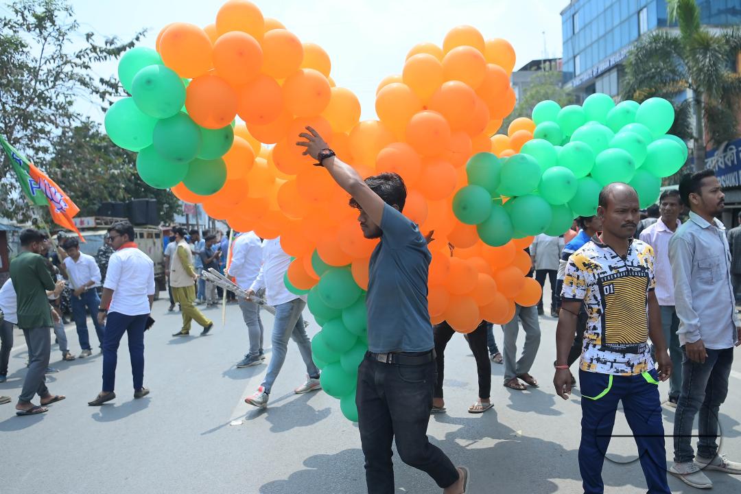 Supporters of the BJP are seen decorating balloons in the party's colours at a rally featuring Tripura Chief Minister Manik Saha, former CM and BJP candidate Biplab Kumar Deb, and Kriti Singh, alongside other leaders, during an election campaign rally in