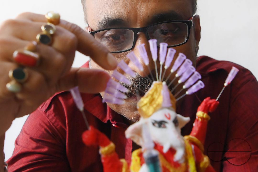 Samiran De, an artist works on an idol of Lord Ganesha made with soup and syringe needles to alert people against drugs, ahead of Ganesh Chaturthi festival, in Agartala