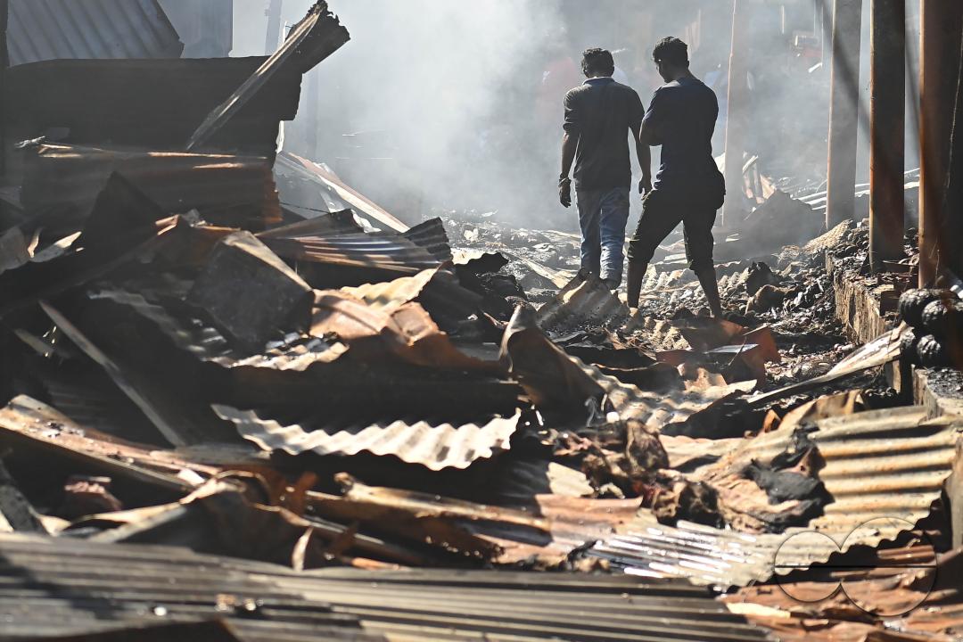 Shop owners and vendors are seen in front of their burnt shops and vegetables stalls in Battala market, the second biggest market in Tripura