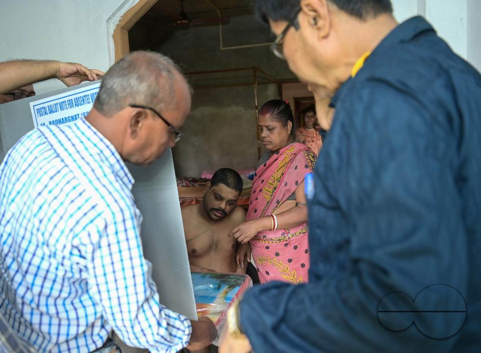 A differently abled boy going through the pre vote procedures before casting his postal ballot vote with the assistance of her family members at her house in front of the team of election officials and security personnel in Agartala