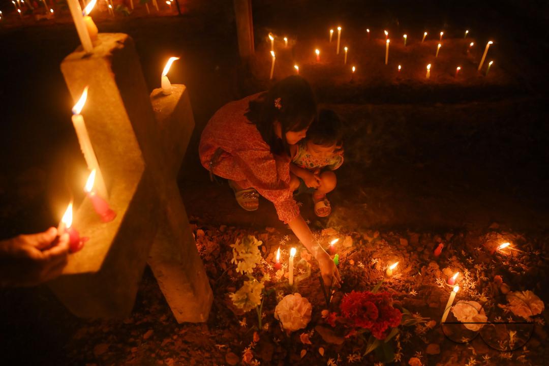 Christians offer prayers next to the graves of their family members at a cemetery during "All Souls Day" on the outskirts of Agartala