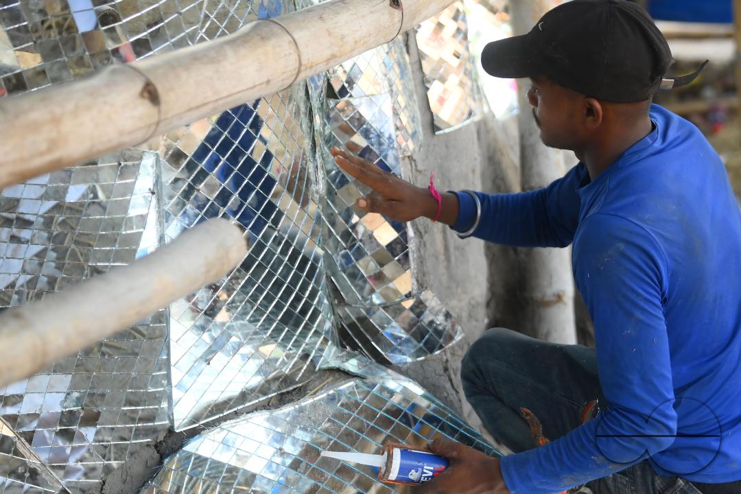 An artist is pasting glass pieces to make a 41 feet tall Ganesh idol, fully covered by glass, ahead of Ganesh Chaturthi festival in a pandal in Ranir bazar